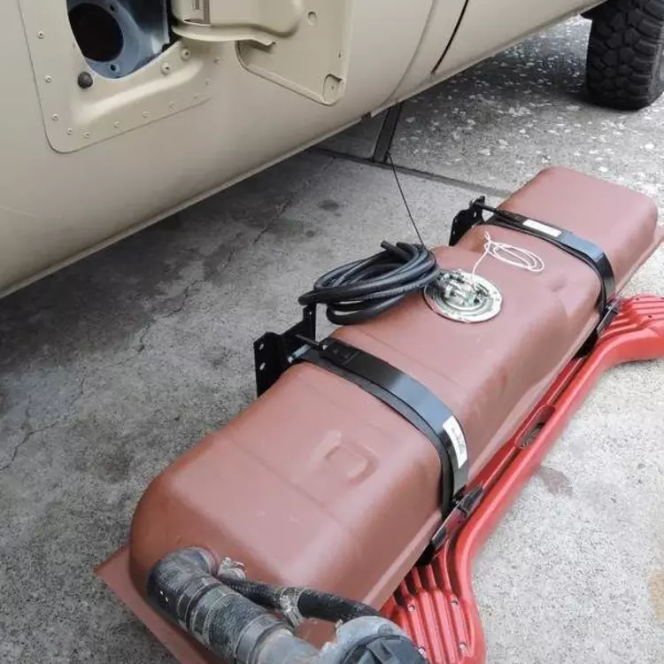 gambar tangi Bahan bakar berwarfna merah yang sedang dilepas dari mobil atau kendaraan, dilengkapi dengan selang